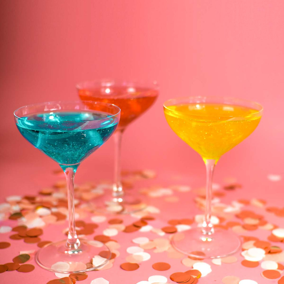 Der perfekte Drink mit Flaschenpost Gin für Silvester in unterschiedlichen glitzernden Farben: rot, blau und gelb mit