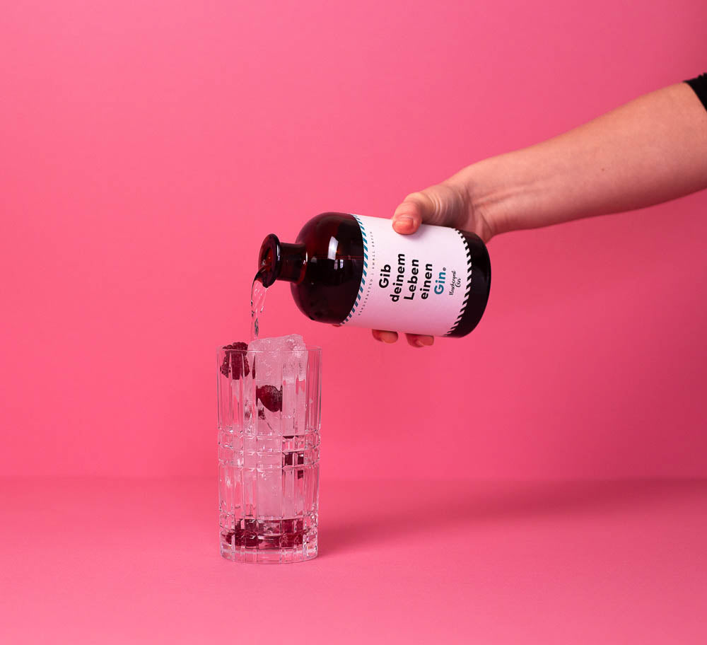 In das Cocktail Glas mit Eis und Himbeeren wird der Gin: Gib deinem Leben einen Gin hinzugegeben
