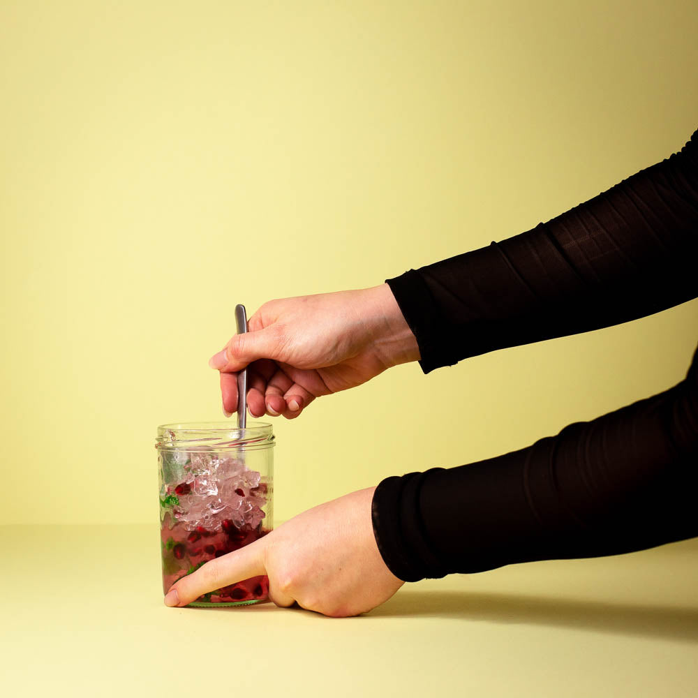 Der Valentinstag Drink Rosa Schlürfer mit Flaschenpost Gin wird umgerührt