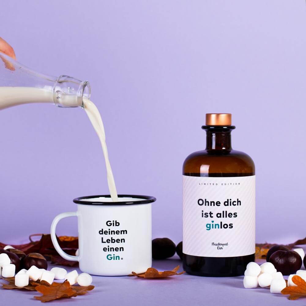 Milch wird in die Emaille Tasse hineingeschüttet für einen wärmenden Drink mit Flaschenpost Gin während der kalten Tage