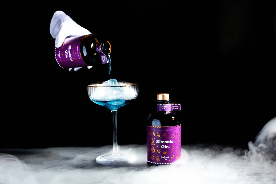 Simsala Gin wird über Eis in das Cocktail Glas hinzugegeben