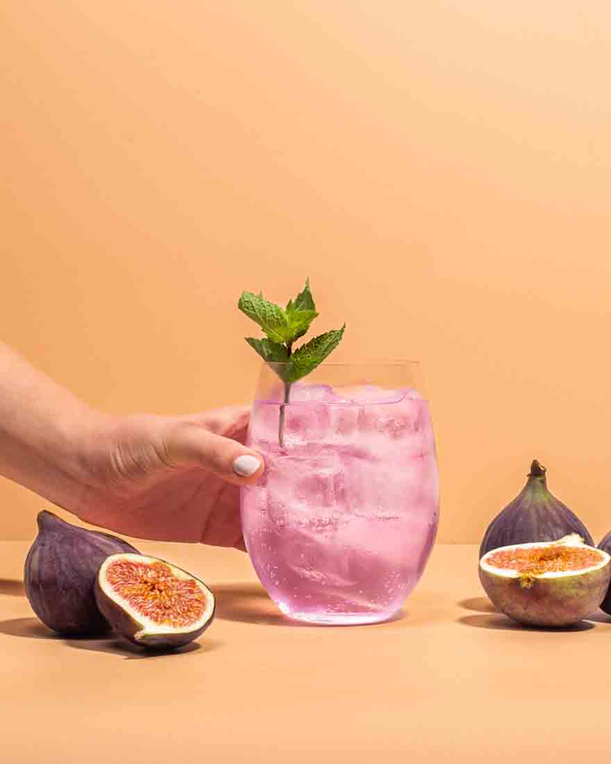 Ein magischer glitzernder Drink mit unserem Simsala Gin mit Glitzer, daneben passend zu seinem Botanical liegen frische Feigen.
