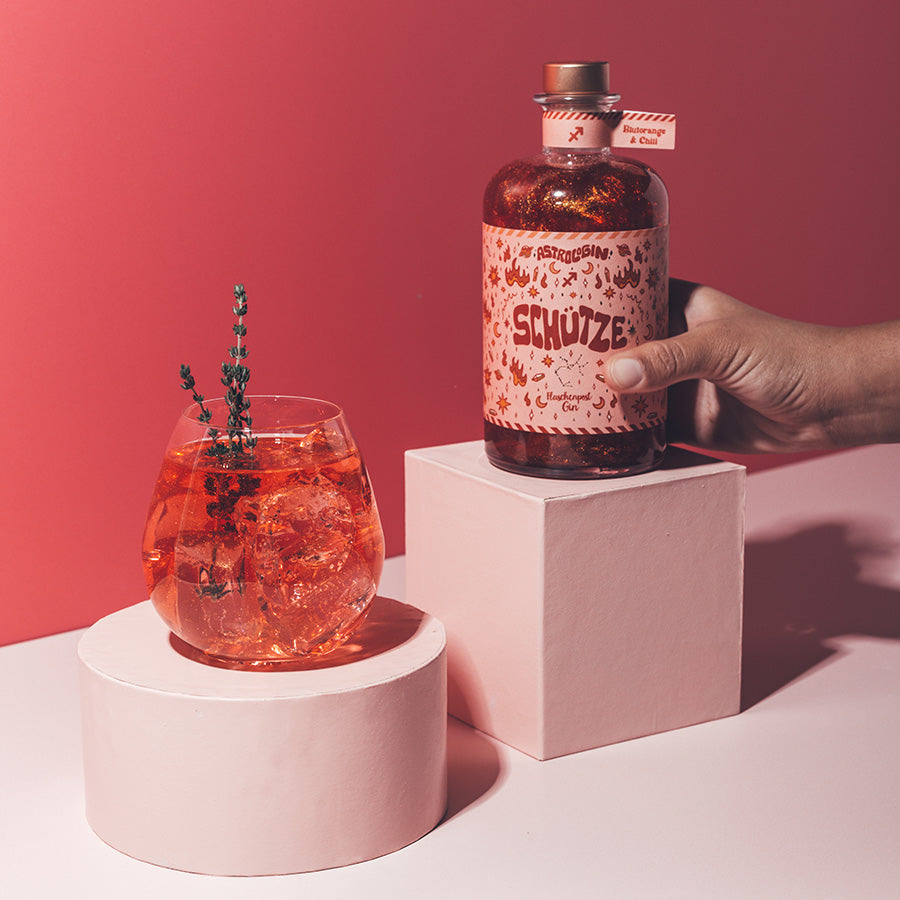 Der erste Sternzeichen Gin mit Glitzer. Unsere AstroloGin Edition. Zu sehen ist der rote Gin mit Glitzer passend zum Element Feuer mit dem Etikett für das Sternzeichen Schütze. Mit dem Geschmack von Geschmack von Chili und Blutorange lässt sich der perfekte Drink für die feurigen Sternzeichen kreieren.   