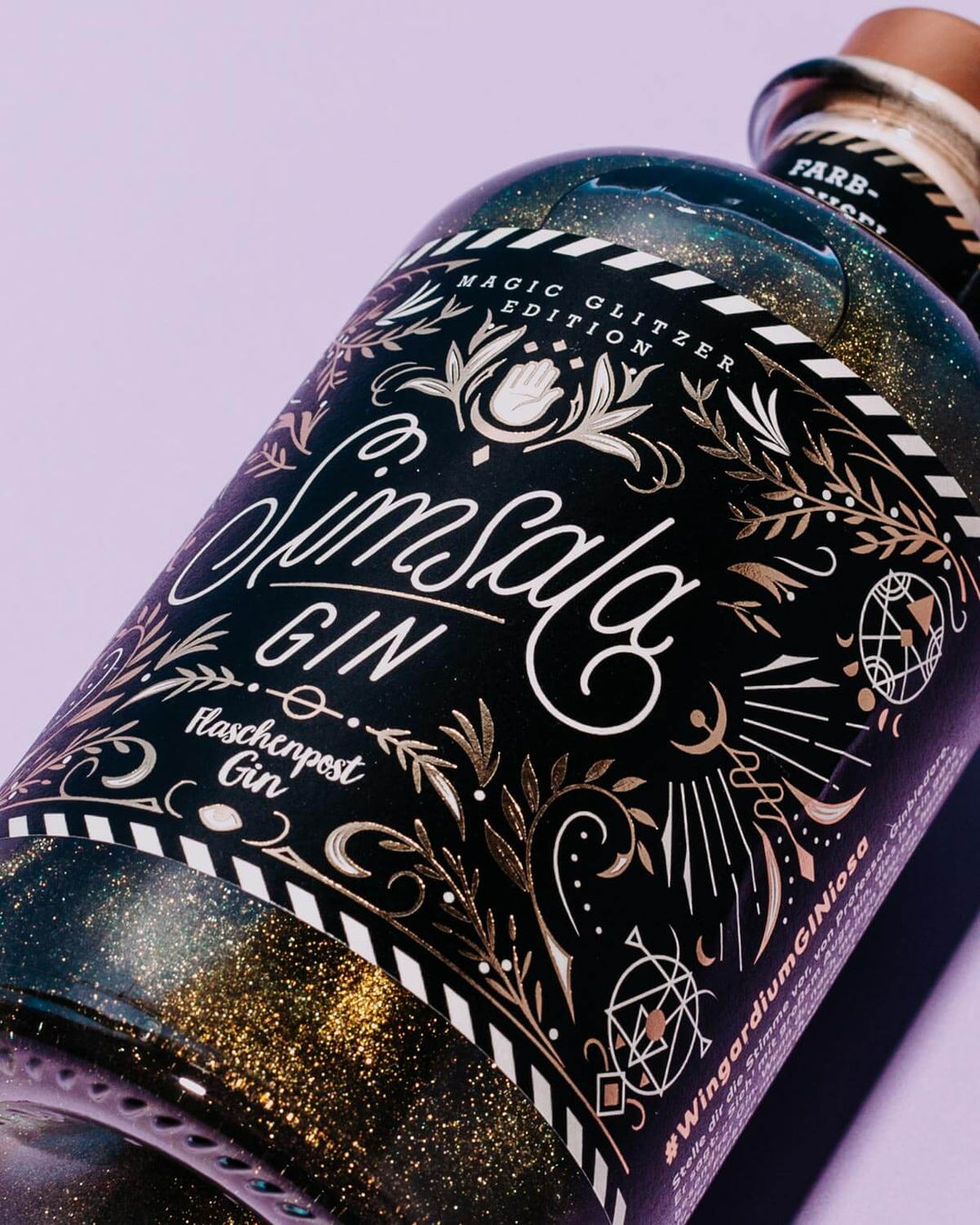 Das Etikett Simsala Gin von Flaschenpost Gin gleicht mit seinen goldenen Details auf schwarzem Hintergrund einem magischen Kunstwerk. Kreiert von dem Special Artist Nim Ben-Reuven aus New Yorck.